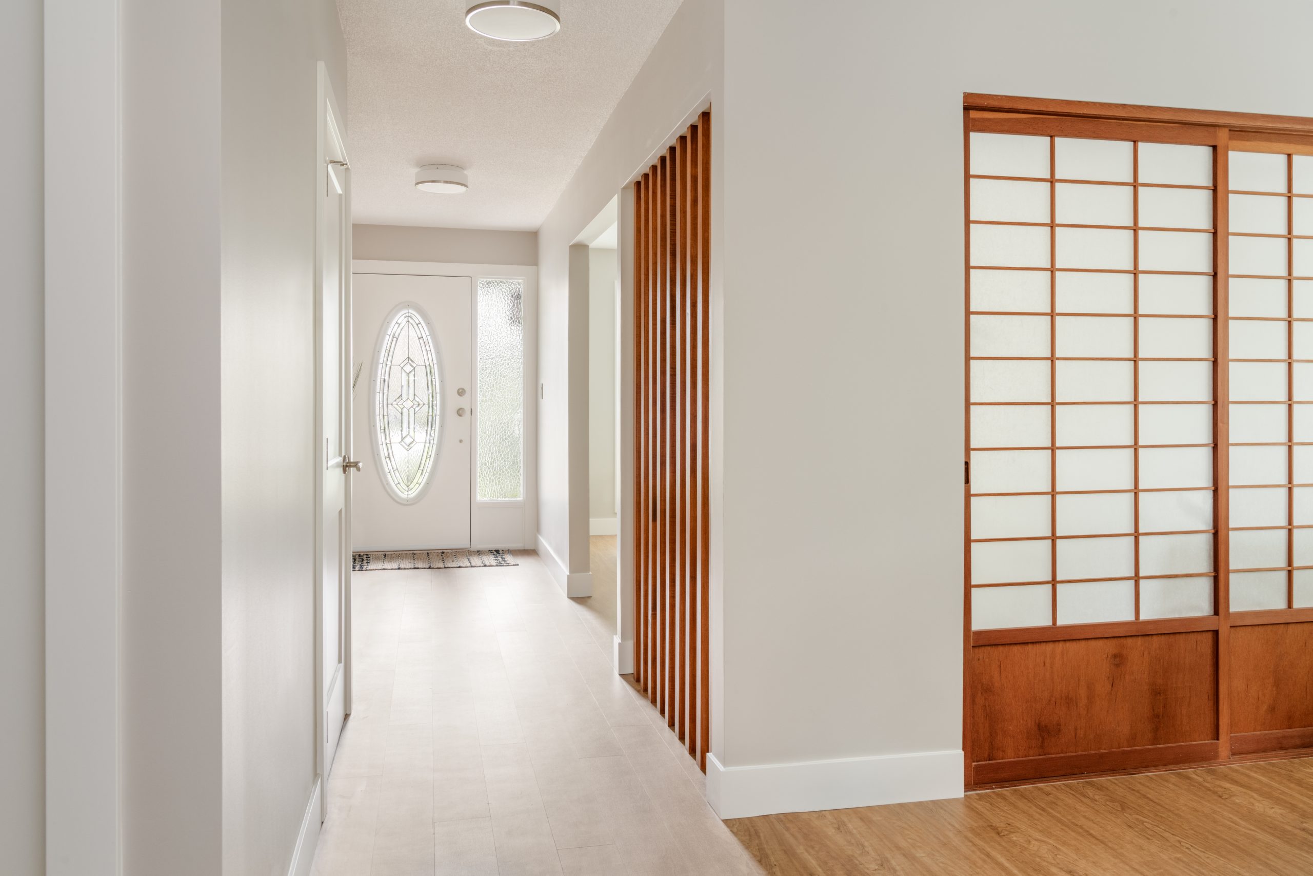 Minimalist entryway with vertical wood slats and shoji-style sliding doors, creating a calm, cohesive transition between spaces.