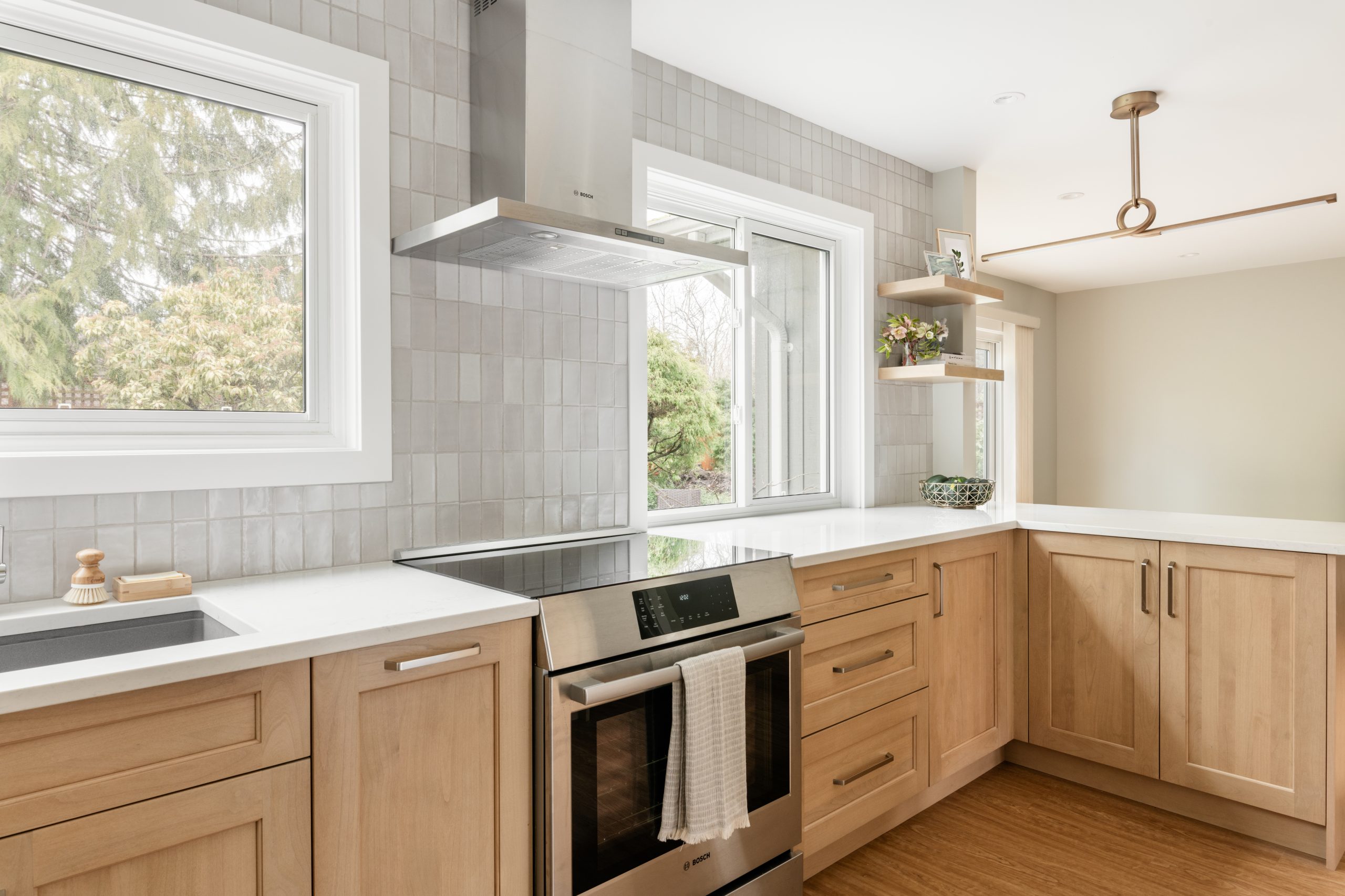 Warm wood cabinetry and open shelving create a bright, functional kitchen space — custom design by Coastal Accents Millwork in Victoria BC.